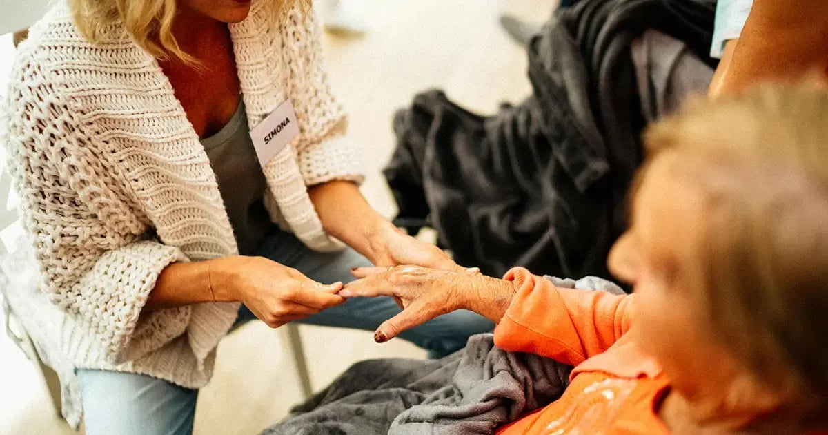 A caregiver from a private Spitex massages the hand of an elderly woman.