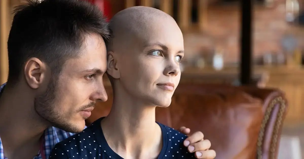 Woman with cancer looks out the window with her partner