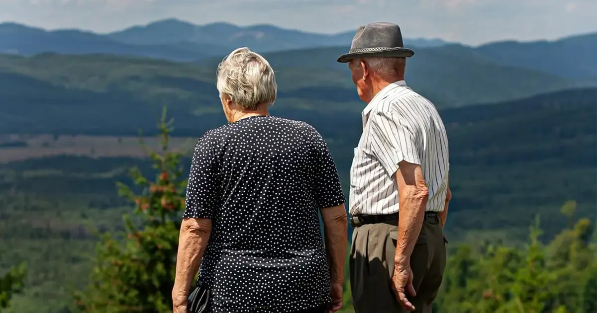 An elderly couple stands on a viewing platform overlooking the picturesque landscape of the Swiss Alps, symbolizing the need for care in Switzerland.