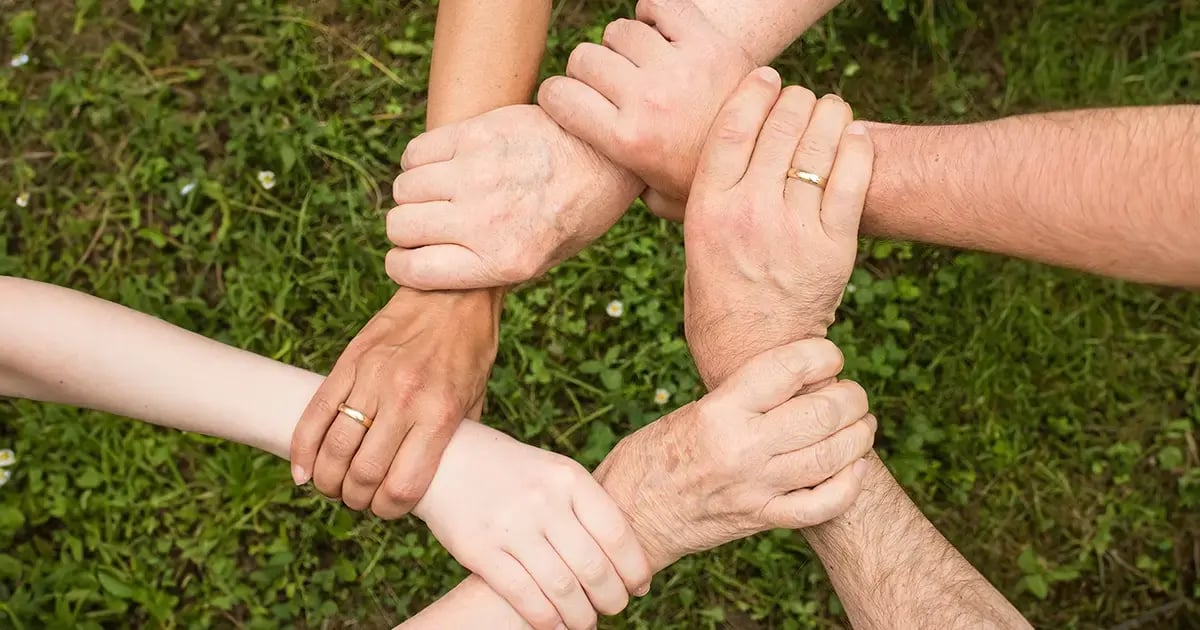 mehrere sich gegenseitig an den Handgelenken haltende Hände
